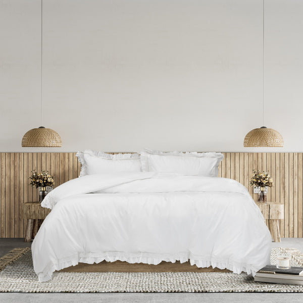 A serene bedroom featuring a white quilt cover set and a wooden headboard, embodying timeless elegance and comfort.