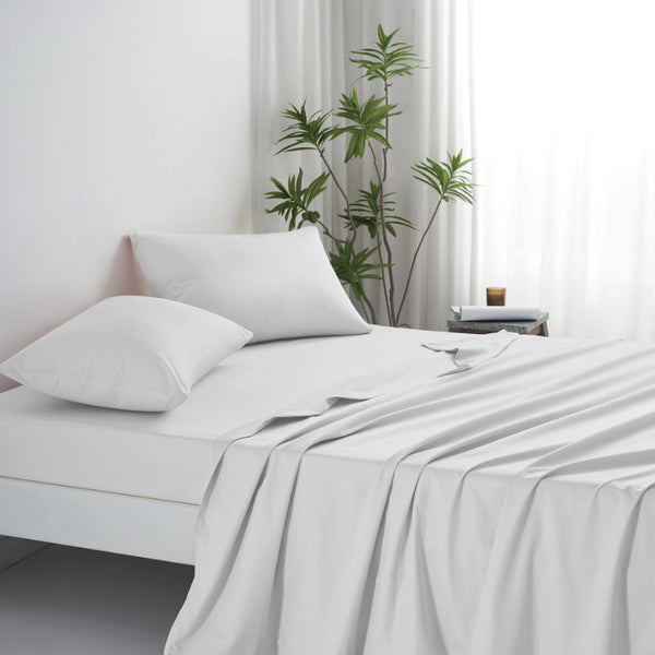 A luxurious bed adorned with a white sheet and pillows, showcasing the elegance of the Amor Opulence Bamboo Cotton Sheet Set.