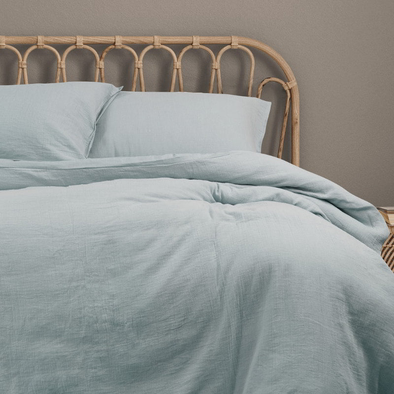 A tranquil bedroom scene with a neatly made bed and a soothing blue quilt cover, inviting relaxation.