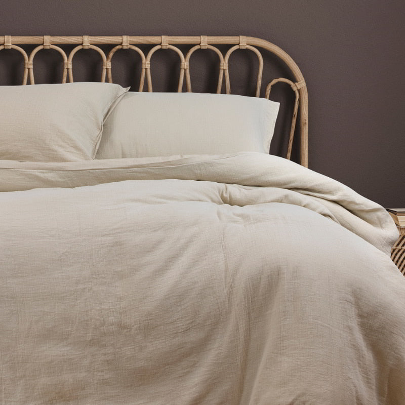 Cosy bed with a white linen quilt cover set, perfect for a warm and inviting bedroom vibe.