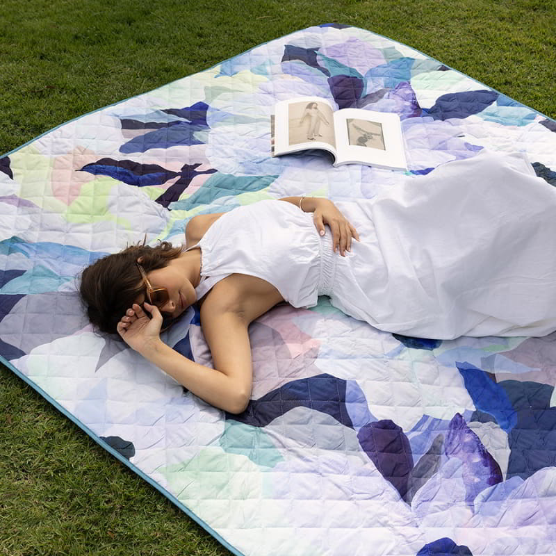 A woman enjoying the comfort of the Bambury Ambrosia Picnic Rug outdoors.