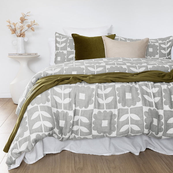 A bed adorned with a grey quilt cover set, featuring a subtle checkerboard and floral design for a serene atmosphere.