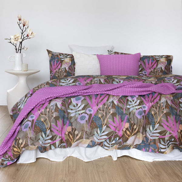 A bed adorned with a reversible quilt cover set featuring a vibrant purple and pink floral print, enhancing bedroom elegance.