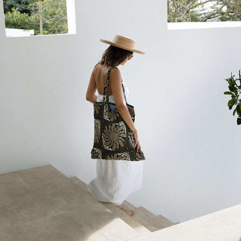 A woman in a white dress, showcasing elegance and poise with the Zinnia Moss Green Tote Bag.