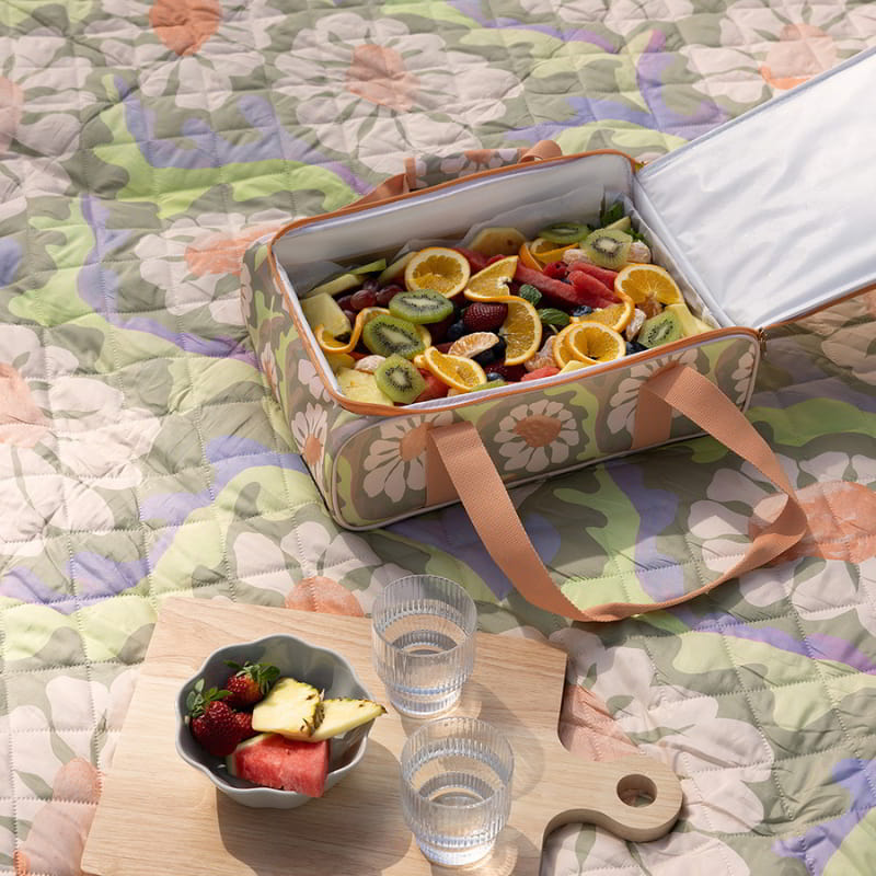 A picnic blanket featuring a Sadie orange food carrier, ideal for outdoor dining and gatherings.