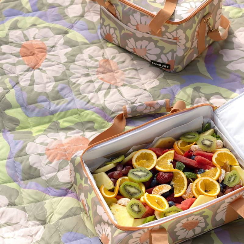 Picnic bags filled with fresh fruits, accompanied by a large, water-resistant Sadie orange picnic rug for outdoor enjoyment.