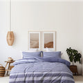 A serene coastal bedroom with a blue striped bed, featuring the Bas Phillips St Tropez Cotton Quilt Cover Set.