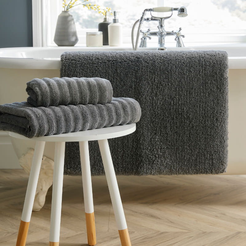 A stylish white bath mat featuring a stool and towels, contributing to a calming and elegant bathroom setting.