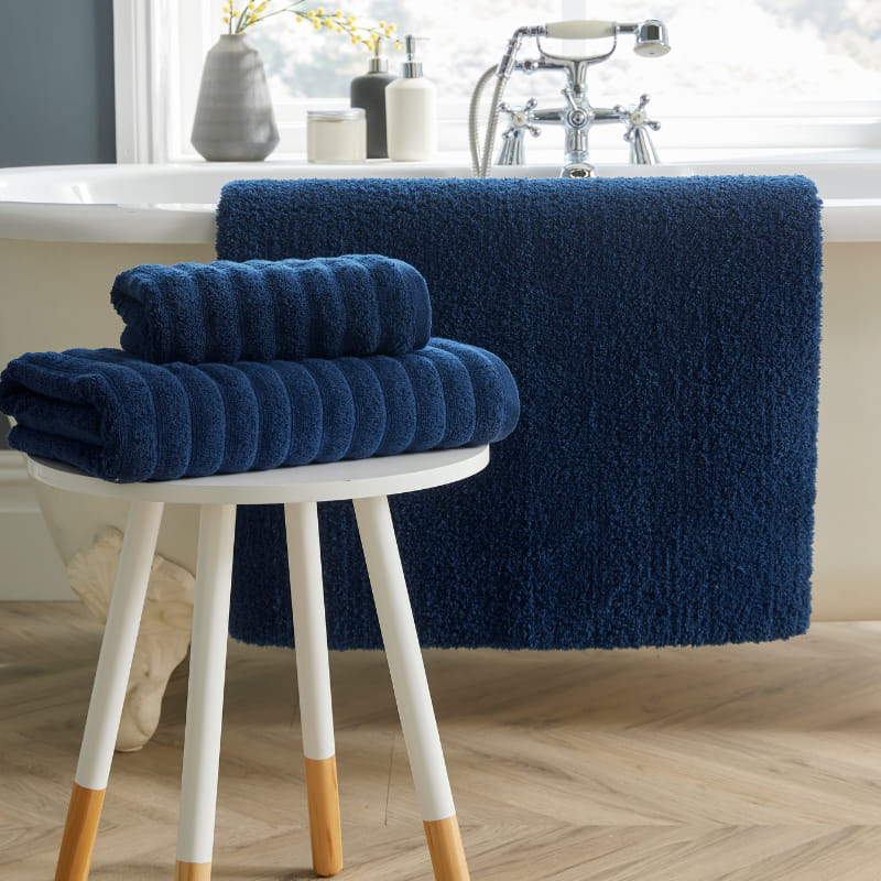 A stylish white bath mat featuring a stool and towels, contributing to a calming and elegant bathroom setting.