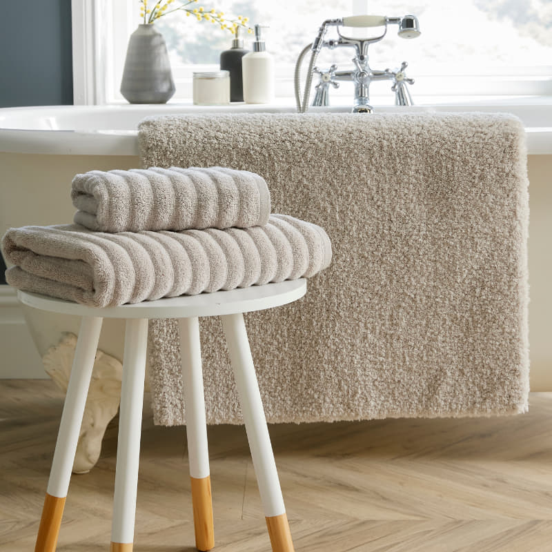 A stylish white bath mat featuring a stool and towels, contributing to a calming and elegant bathroom setting.