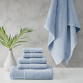 A stack of luxurious blue towels made from eco-friendly materials, placed on a table beside a vibrant green plant.