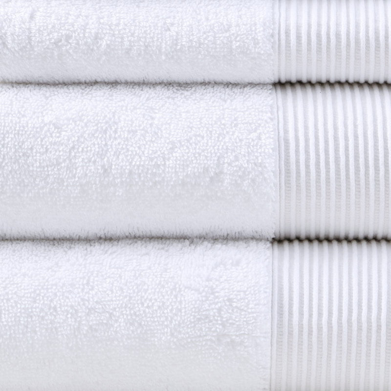 Detailed shot of a stack of luxurious white towels made from eco-friendly Tencel and cotton, promoting sustainability and advanced hygiene.