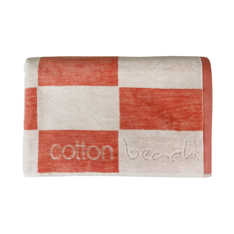 Close up details of a calming coral checkerboard design towel, ideal for a tranquil beach day experience.