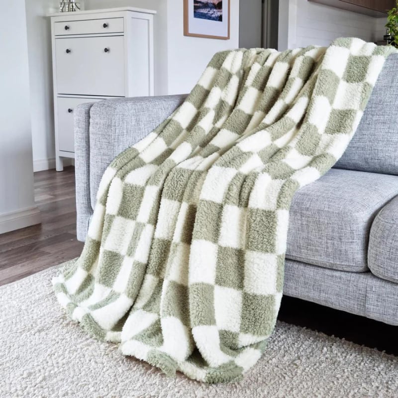 A cosy green and white checkered blanket on a couch, the perfect blend of fashion and cosiness for chilly nights.