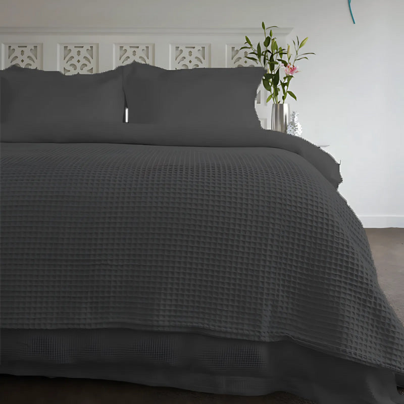 A charcoal blanket is elegantly laid on a cosy bedroom, showcasing a minimalist aesthetic and a sense of tranquility.