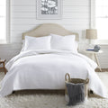 Serene white bed adorned with a soft comforter and pillows, showcasing a classic striped pattern with fun pom-pom accents.