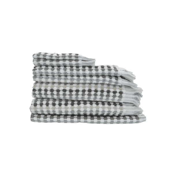 A stack of grey and white checker-patterned bath linens, showcasing luxurious softness and stylish pom-pom fringes for elegant decor.