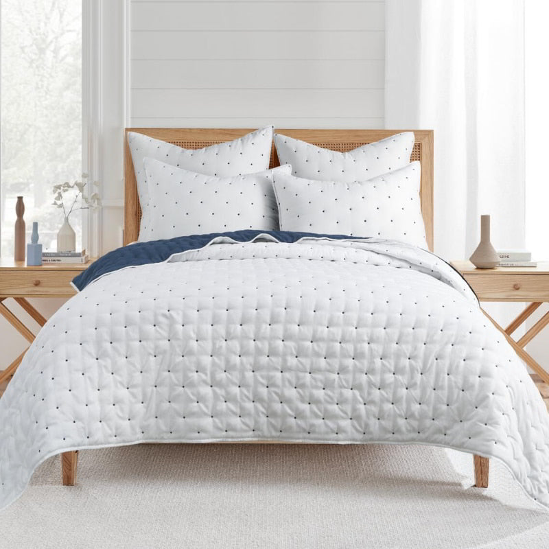 The coverlet set showcases a playful white and blue polka dot design, enhancing the serene atmosphere of any bedroom.