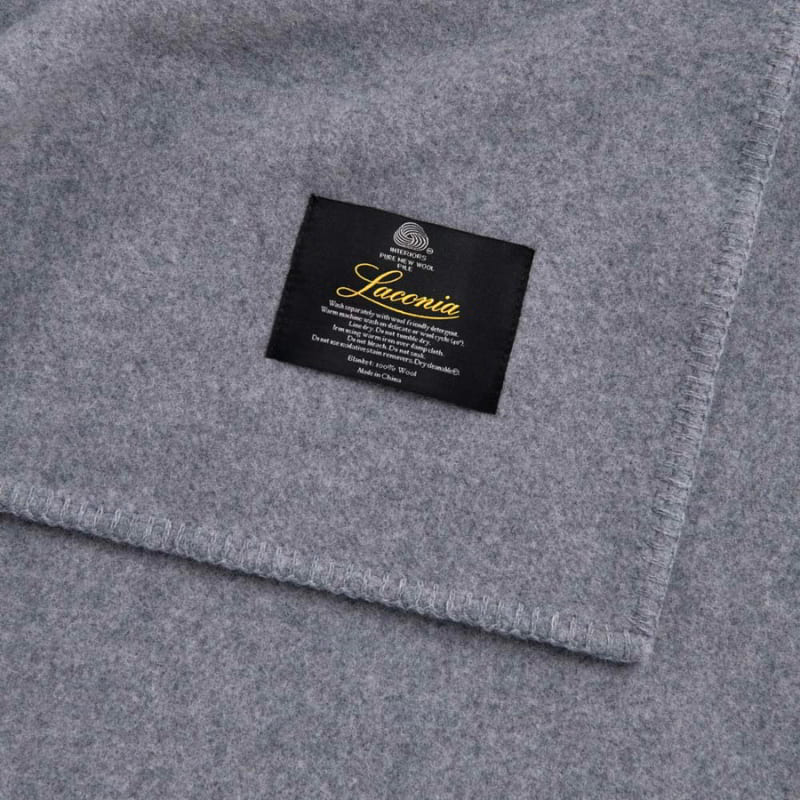 The zoom in shot of grey blanket with Laconia tag that is woven from premium Australian pure new wool.