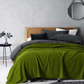 A bed with moss green blanket of Laconia that is made from premium Australian pure new wool.