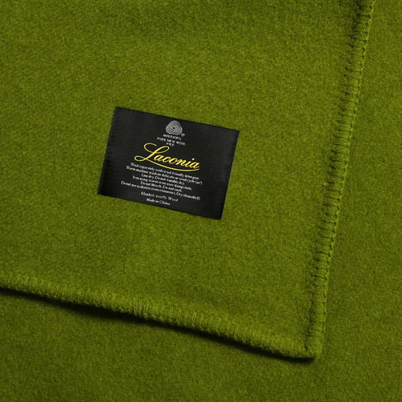 The zoom in shot of moss green blanket with Laconia tag that is woven from premium Australian pure new wool.