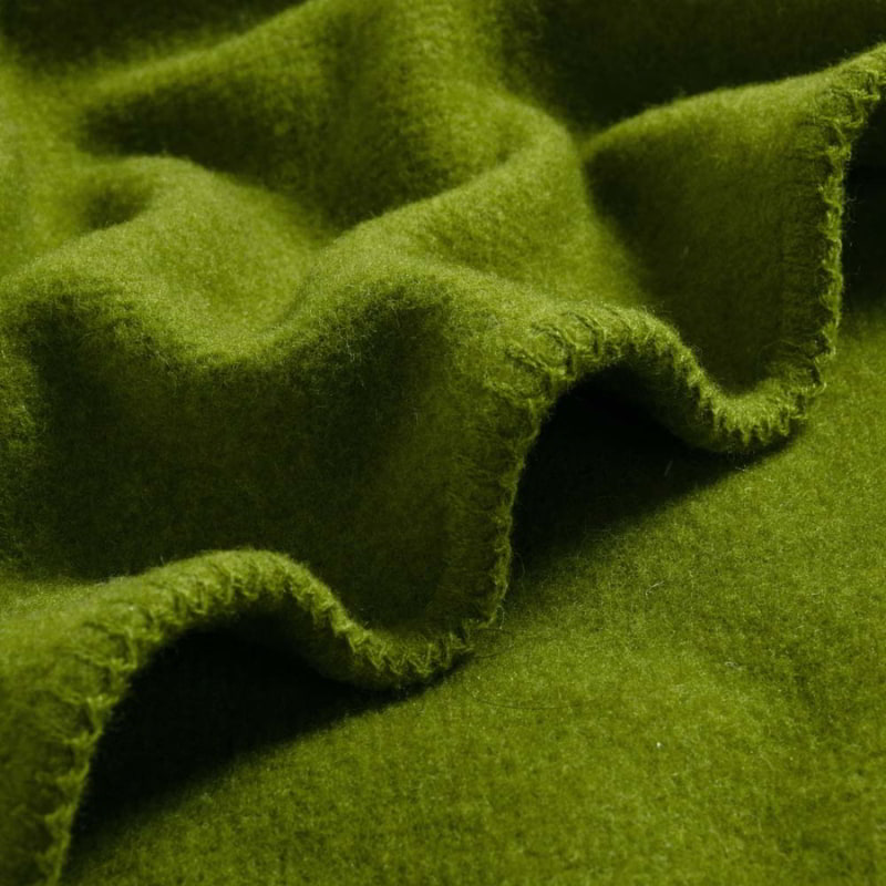 The moss green blanket of Laconia offers durability, warmth, and comfort for all seasons.