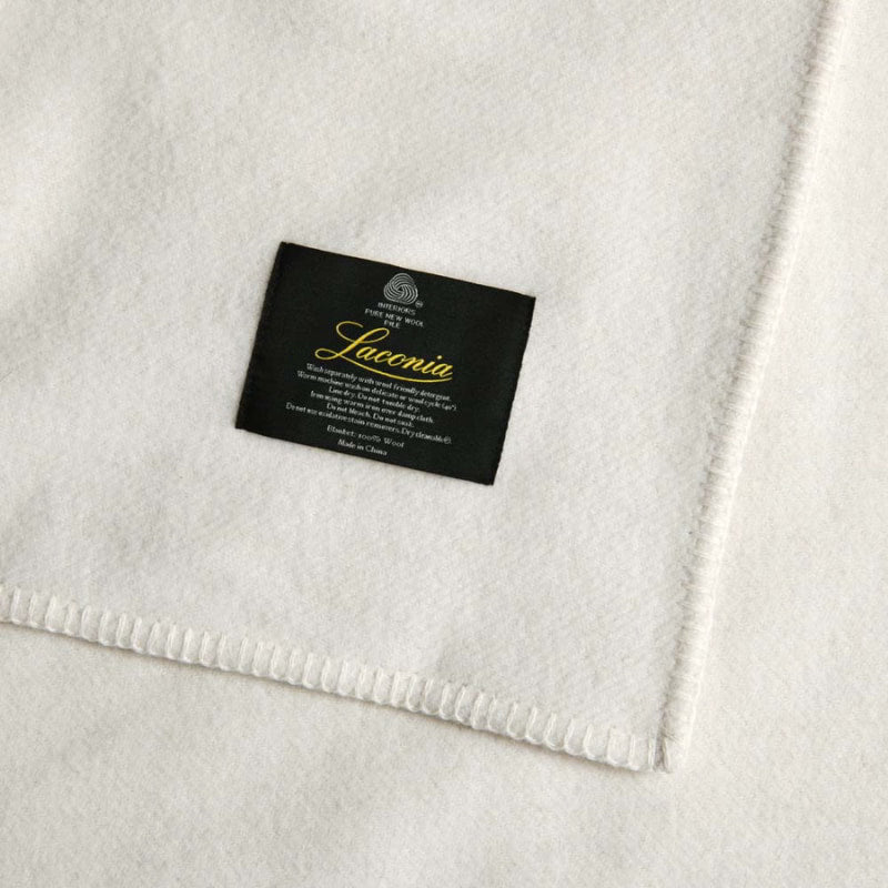 The zoom in shot of natural blanket with Laconia tag that is woven from premium Australian pure new wool.