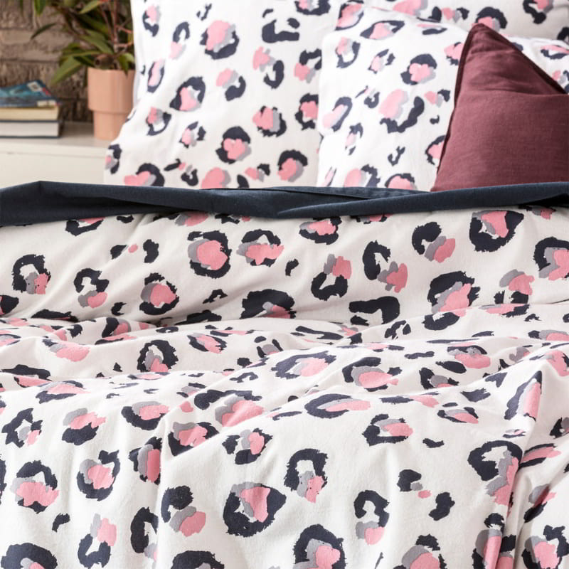 Zoom details of a stylish bed featuring a white and pink leopard print quilt cover, designed for warmth and softness during cold winter nights.