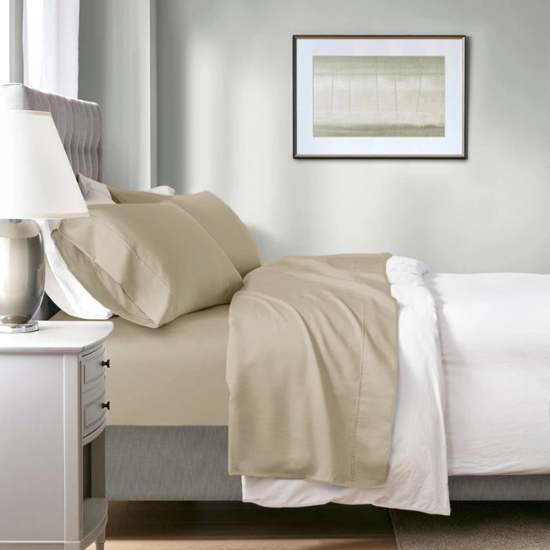 A neatly made bed featuring a bone sheet and bone pillowcases, showcasing the softness and breathability of the Renee Taylor Sheet Set.