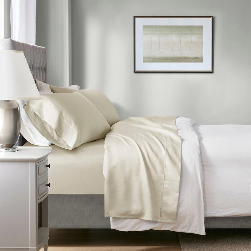 A neatly made bed featuring an ivory sheet and ivory pillowcases, showcasing the softness and breathability of the Renee Taylor Sheet Set.