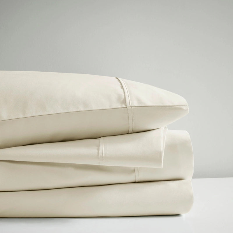 A stack of ivory sheet set, showcasing the luxurious 700 Thread Count Renee Taylor Sheet Set.