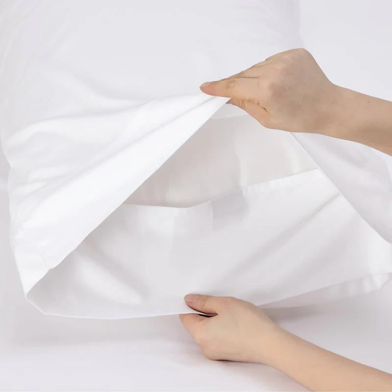 A person inserting a pillow into a pillowcase, showcasing the luxurious white pillowcase of Renee Taylor for optimal comfort.