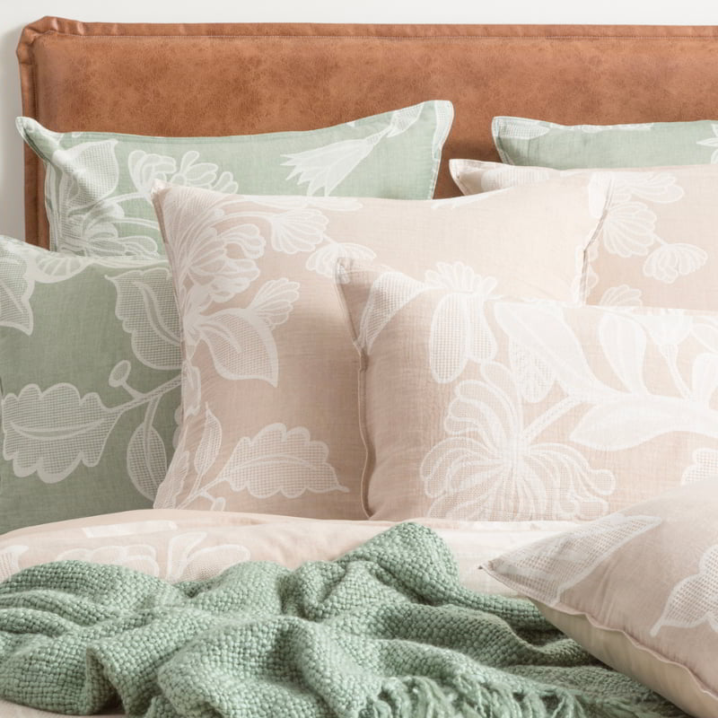  Elegant bed set with pillows showcasing intricate floral designs and a lush green blanket, accented by waffle pattern leaves.