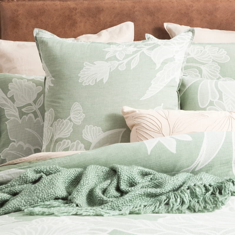 Immerse yourself in the opulence of a bed embellished with plush green and white pillows and blankets, enhanced by a captivating floral sage green quilt cover set.