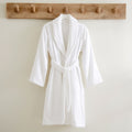 A white robe featuring a sleek style and front pockets, perfect for a comfortable home spa experience.