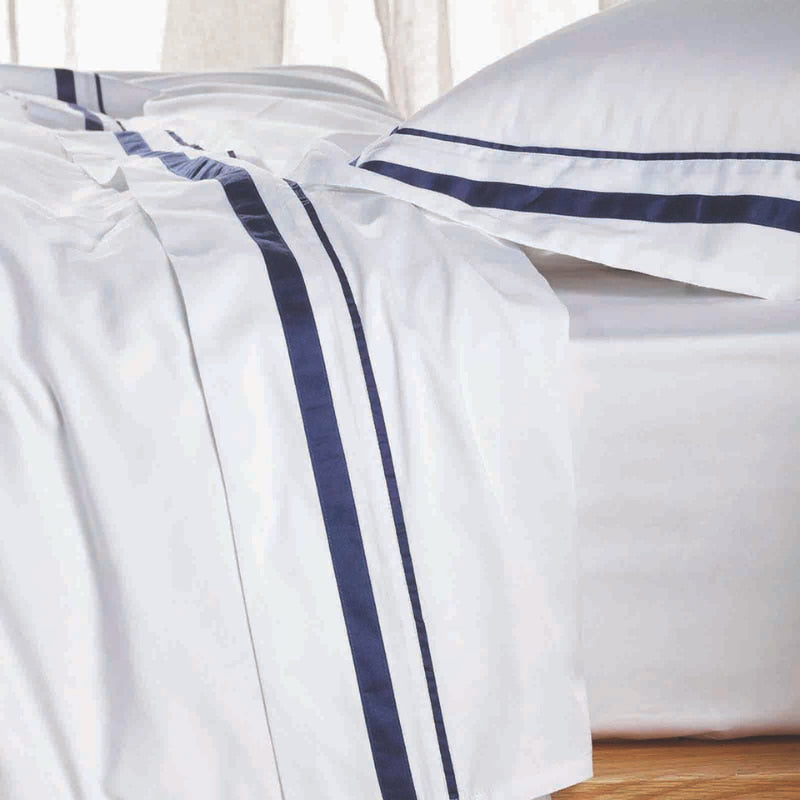 Close up details of an opulent Renee Taylor Cloud Sheet Set featuring 1000-thread count Egyptian cotton, available in white with chic navy edges.