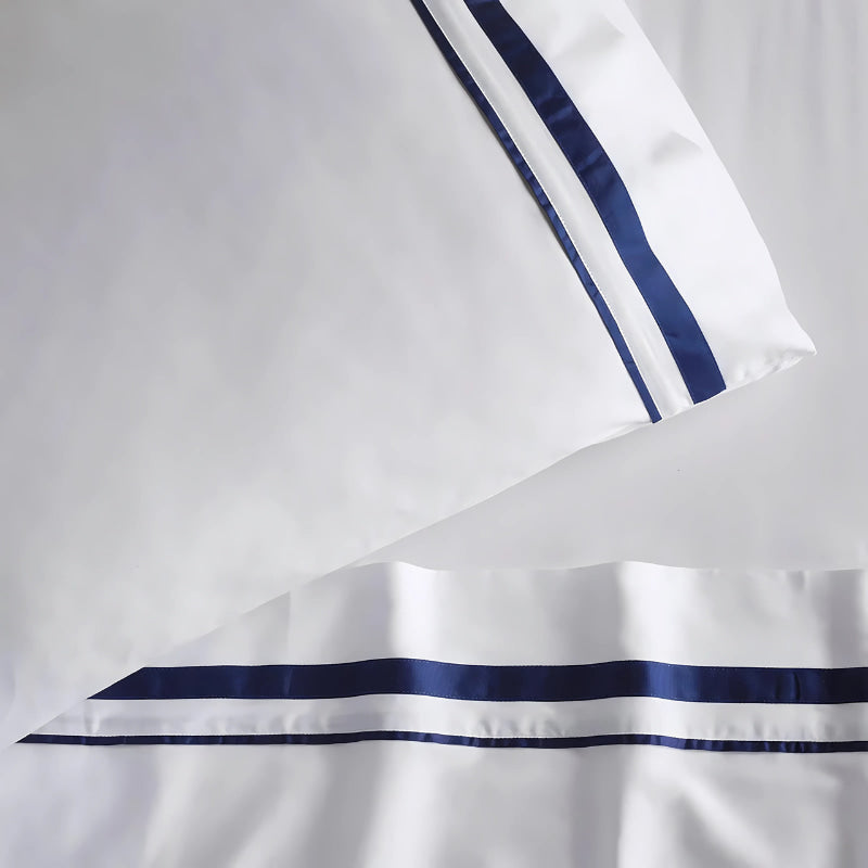 Close up look of the opulent Renee Taylor Cloud Pillowcases featuring 1000-thread count Egyptian cotton, available in white with chic navy edges.