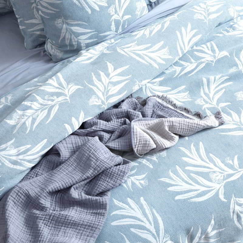 A sophisticated blue and white bed adorned with a stylish leaf print, creating a tranquil atmosphere.