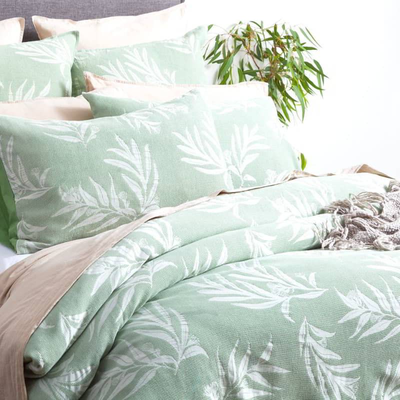 Luxurious bed adorned with green and white bedding, showcasing the serene charm of the Native Quilt Cover set.