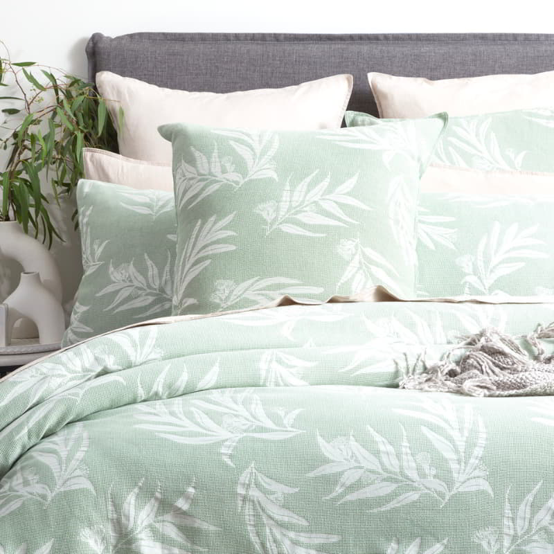 A cosy bed with green and white leaf print, showcasing the serene charm of the Native Quilt Cover set.