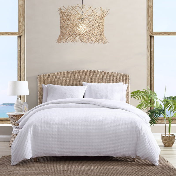 Cozy white bed featuring a tropical-themed quilt cover set.
