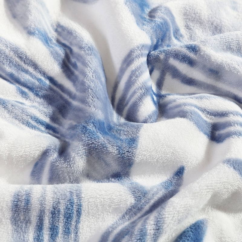 Detailed shot of a soft plush polyester throw with tranquil blues palm leaf design for warmth.