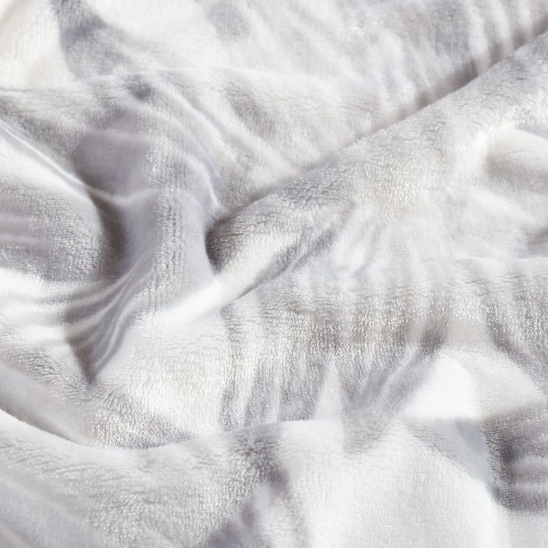 Detailed view of a soft plush polyester throw with soft grey hue palm leaf design for warmth.