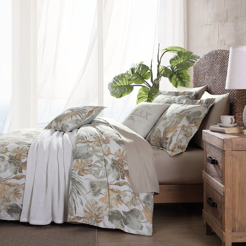 Side view of a tropical print quilt cover set featuring green and gold tones enhances a cosy bedroom atmosphere for restful sleep.