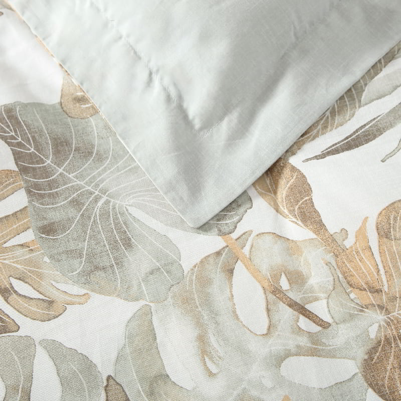 Closer look of a tropical print quilt cover set featuring green and gold tones enhances a cosy bedroom atmosphere for restful sleep.