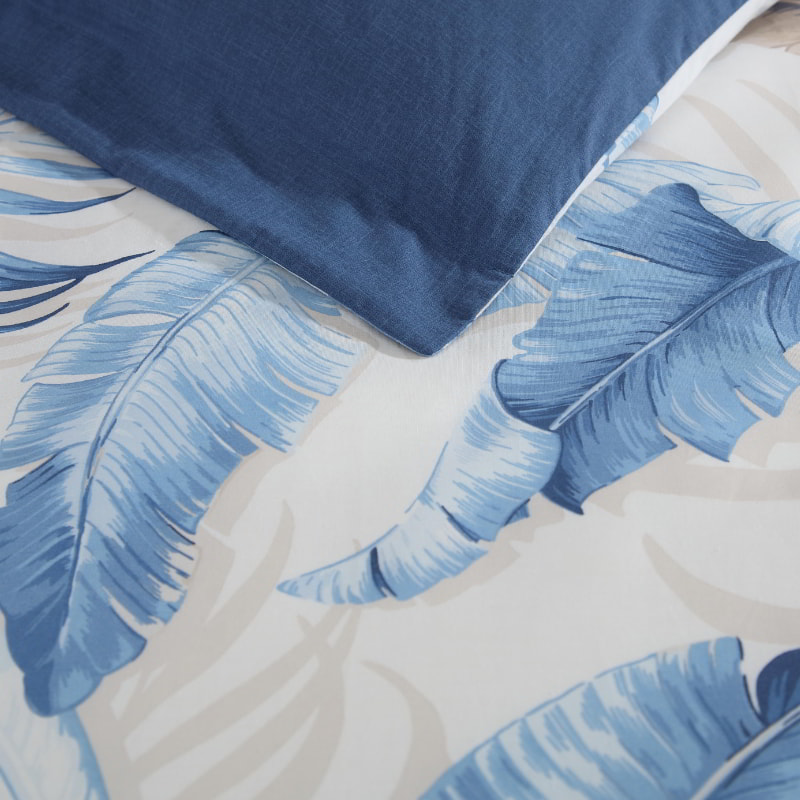 Stylish blue quilt cover with a coordinating pillow, adorned with a tropical leaf pattern for a relaxing bedroom atmosphere.