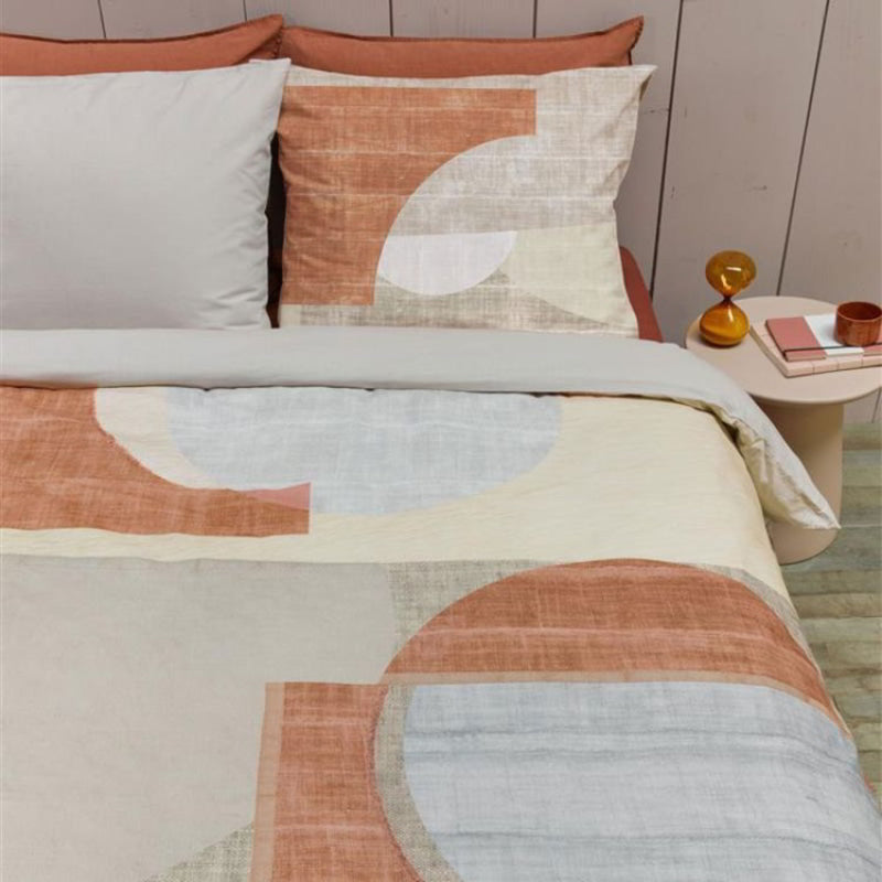 alt="High-quality cotton quilt cover with a modern graphic print in natural and terracotta colours. The printed linen texture on the background adds depth to the design, while the reverse side is a solid sand colour."