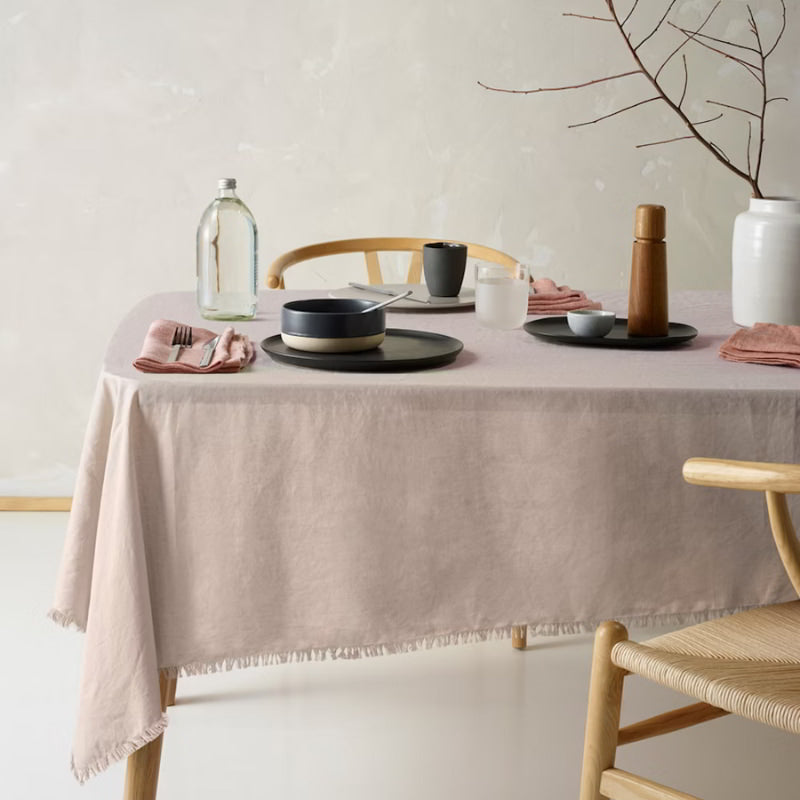 An elegant natural tablecloth made of linen and cotton, featuring a soft feel, fringe edges, and a versatile design for any occasion.