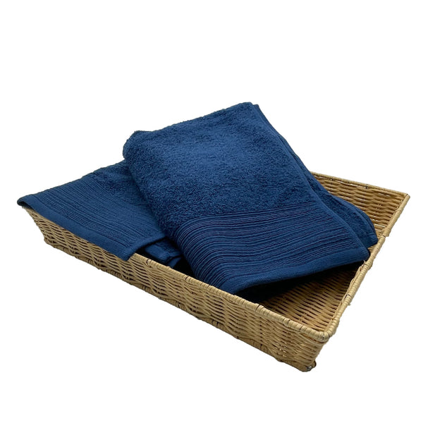 Two navy bath towels elegantly placed in a basket, highlighting their luxurious softness and stylish appeal for a refined bathroom.