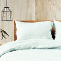 A cosy bed adorned with the elegant linen quilt cover set in a misty hue.